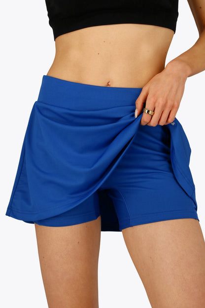 Woman wearing the Osaka women floucy skort princess blue with logo in grey. Front detail short view