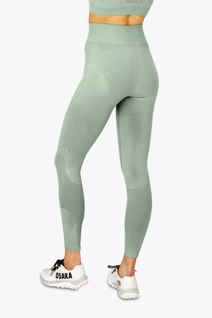 Woman wearing the Osaka women shimuresu leggin in jadeite with logo in grey. Back view