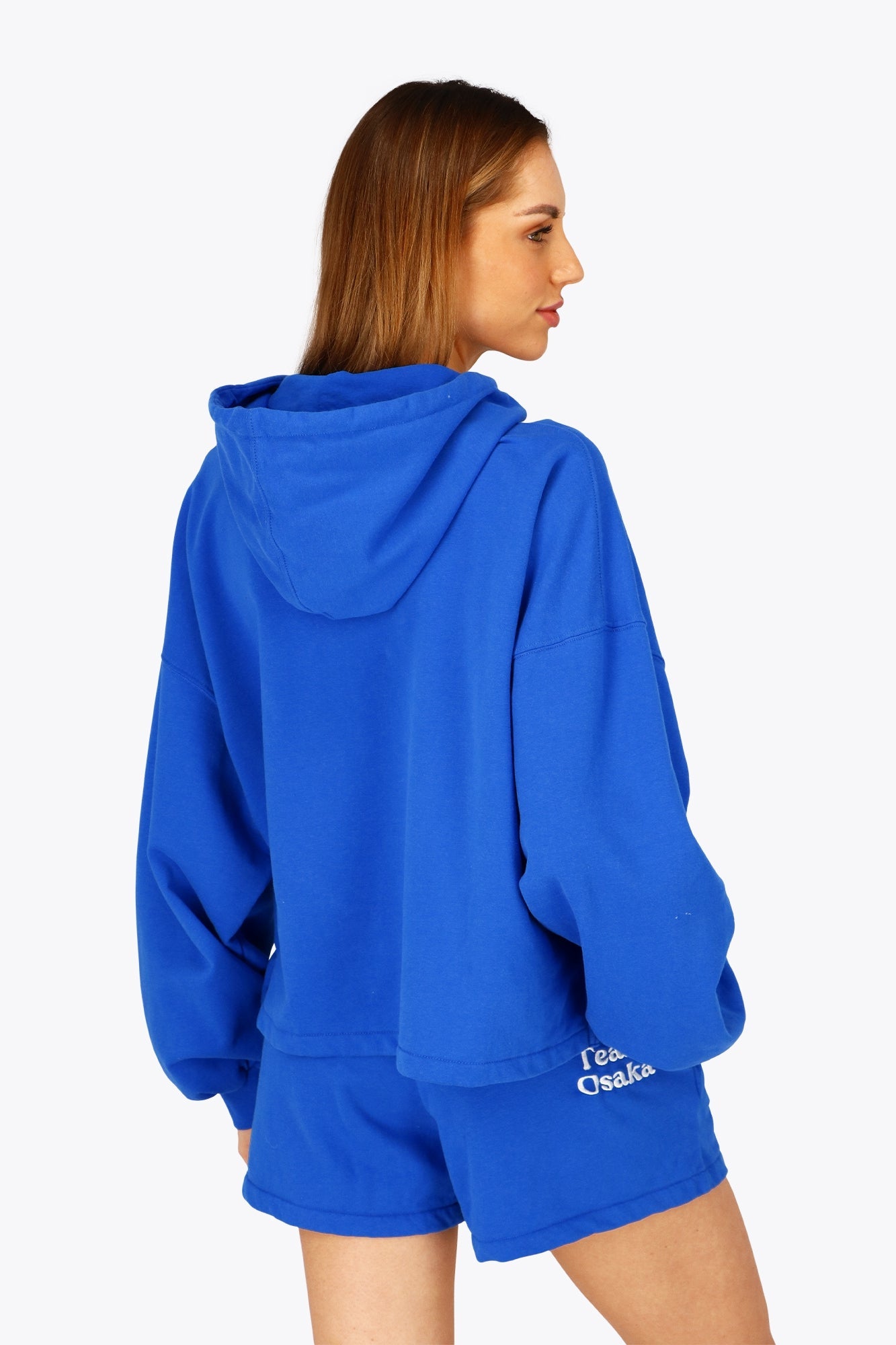 Woman wearing the Osaka women cropped hoodie inprincess blue with college logo in white. Back view