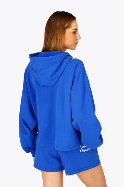 Woman wearing the Osaka women cropped hoodie inprincess blue with college logo in white. Back view