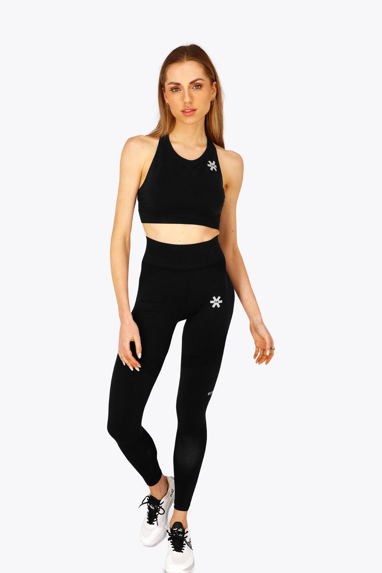 Woman wearing the Osaka women tech sports bra in black with logo in grey. Front view