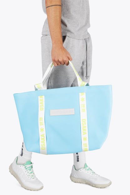 Osaka neoprene Tote bag in light blue with  logo in white. Man wearing the bag
