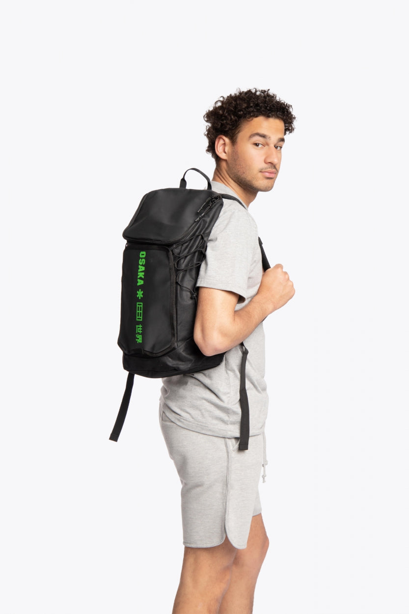 Osaka vision padel backpack in black with logo in green. Man wearing the bag side view