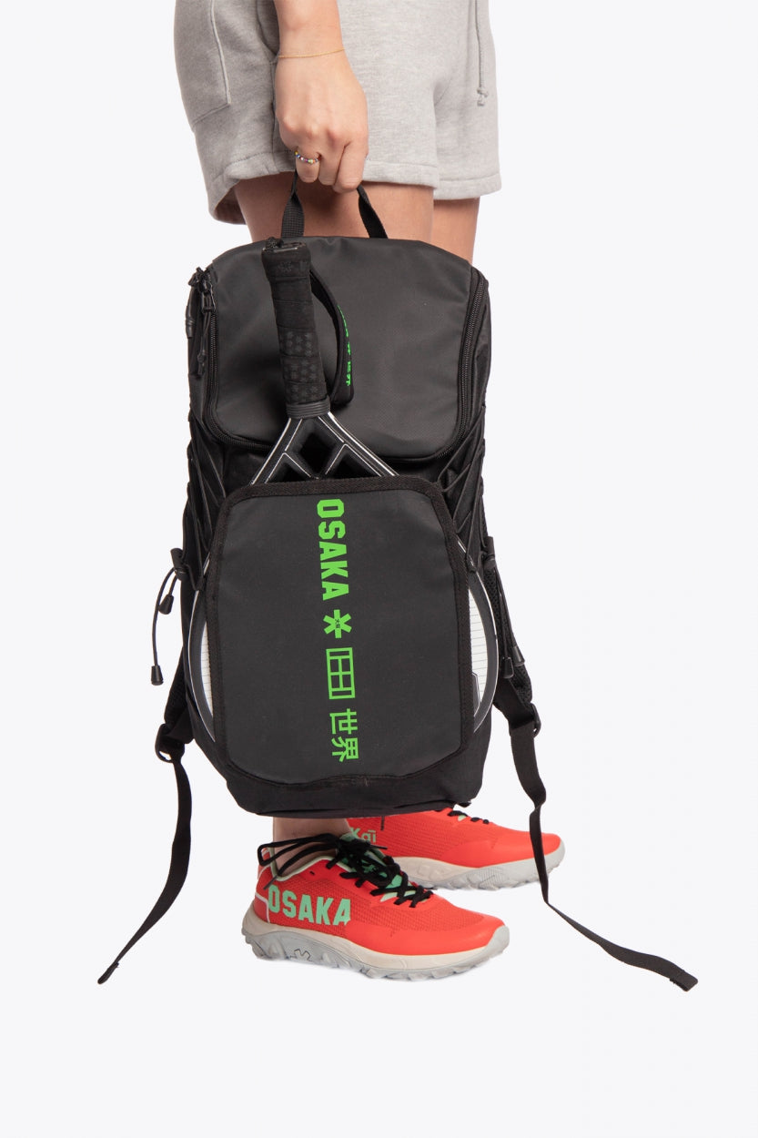 Osaka vision padel backpack in black with logo in green. Woman holding the bag