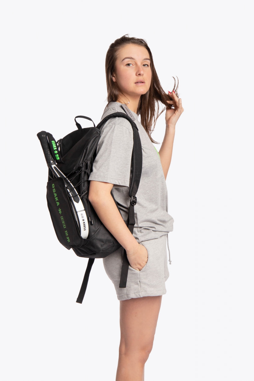 Osaka vision padel backpack in black with logo in green. Woman wearing the bag side view