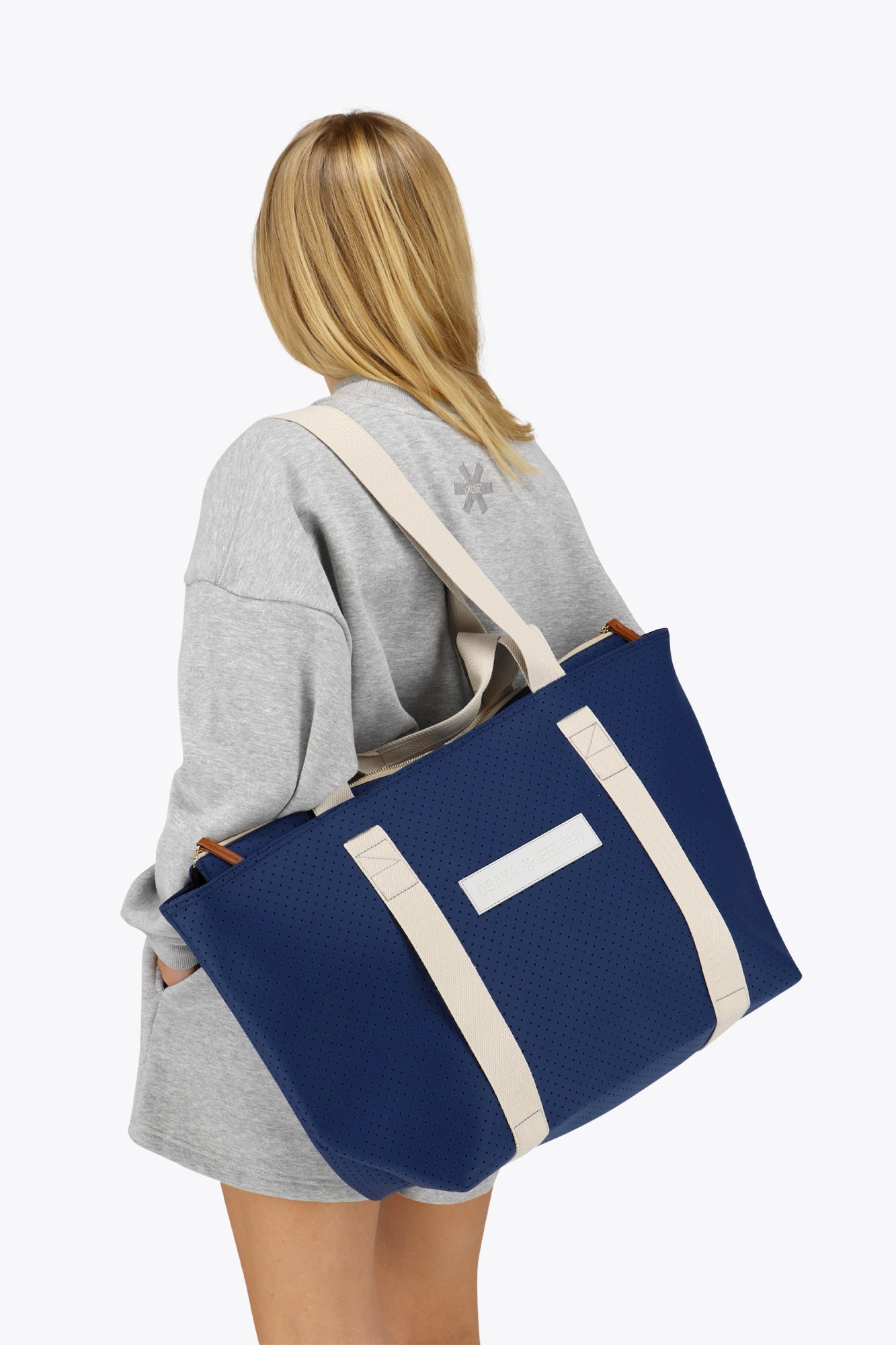 Osaka neoprene Tote bag in navy with structure and logo in white. Woman wearing the bag