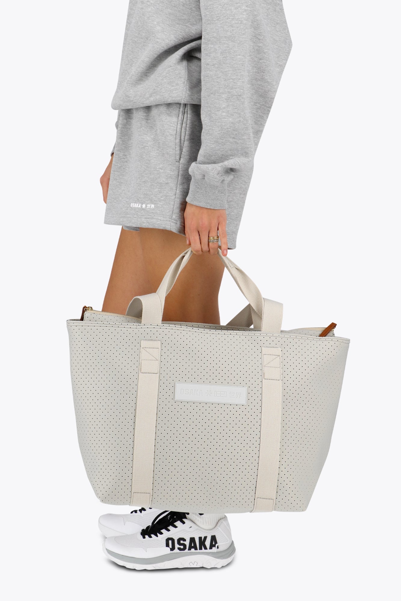 Osaka neoprene Tote bag in light grey with structure and logo in white. Woman holding the bag