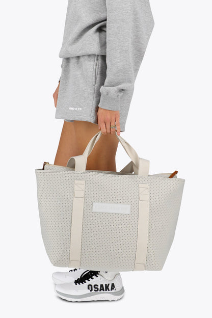 Osaka neoprene Tote bag in light grey with structure and logo in white. Woman holding the bag