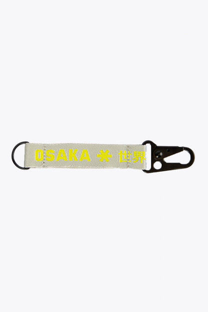 Osaka keychain in light grey with logo in yellow