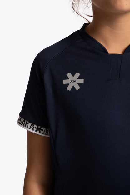 Girl wearing the Osaka Kids Jersey in Navy. Front detail logo view