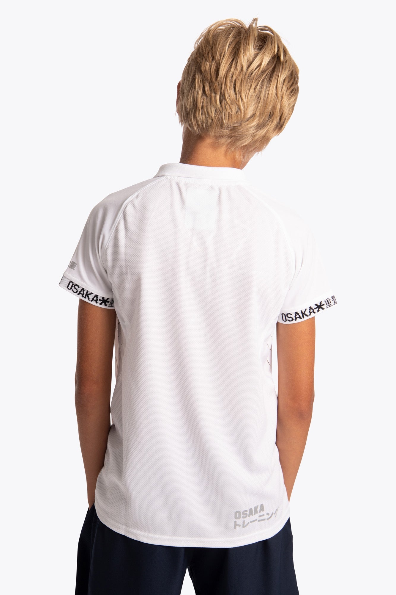 Boy wearing the Osaka Kids Polo Jersey in White. Back view
