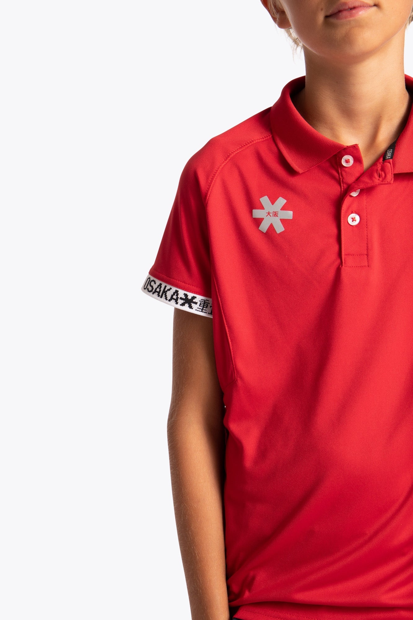 Boy wearing the Osaka Kids Polo Jersey in Red. Front detail logo view
