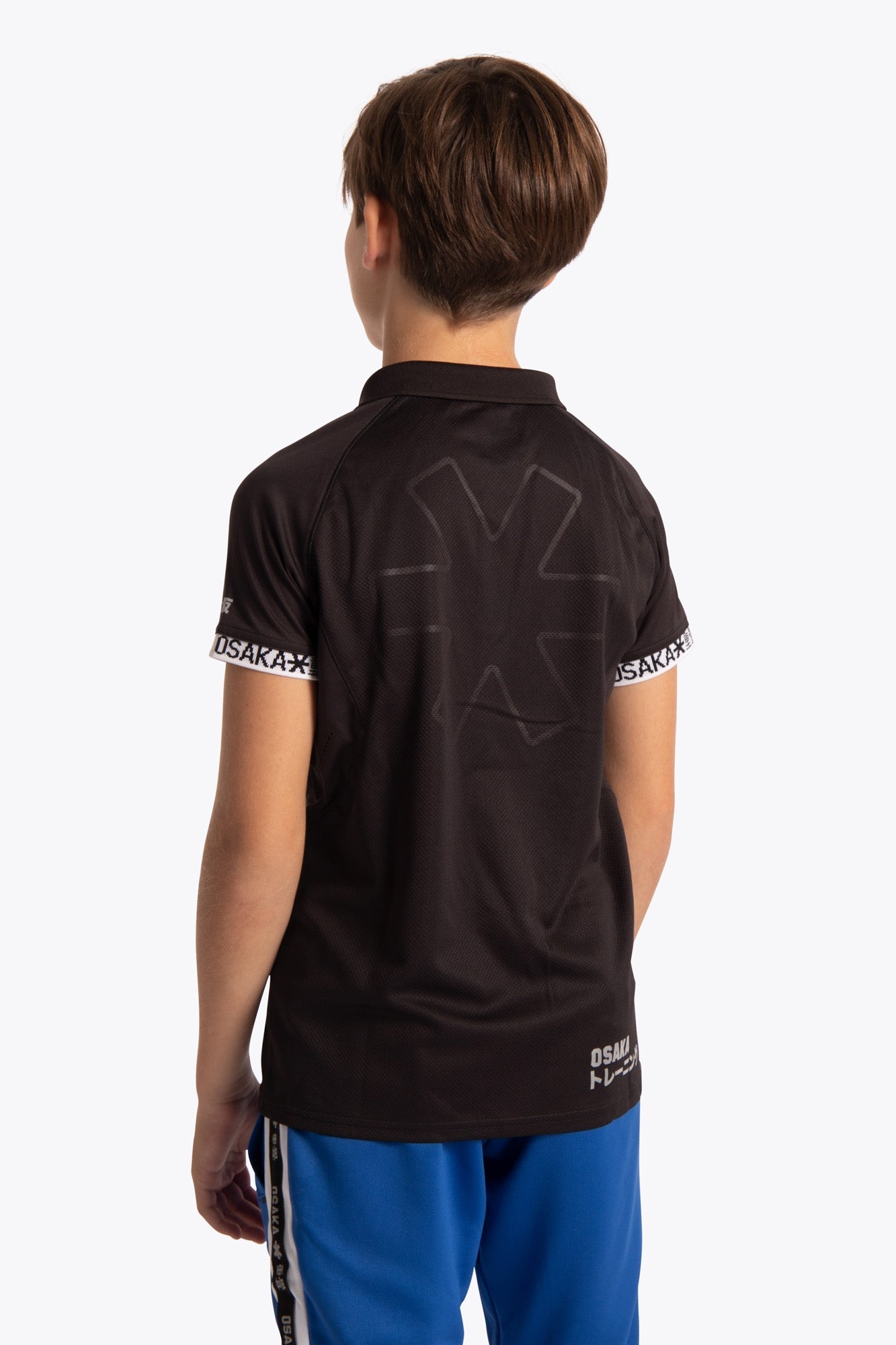 Boy wearing the Osaka Kids Polo Jersey in Black. Back view