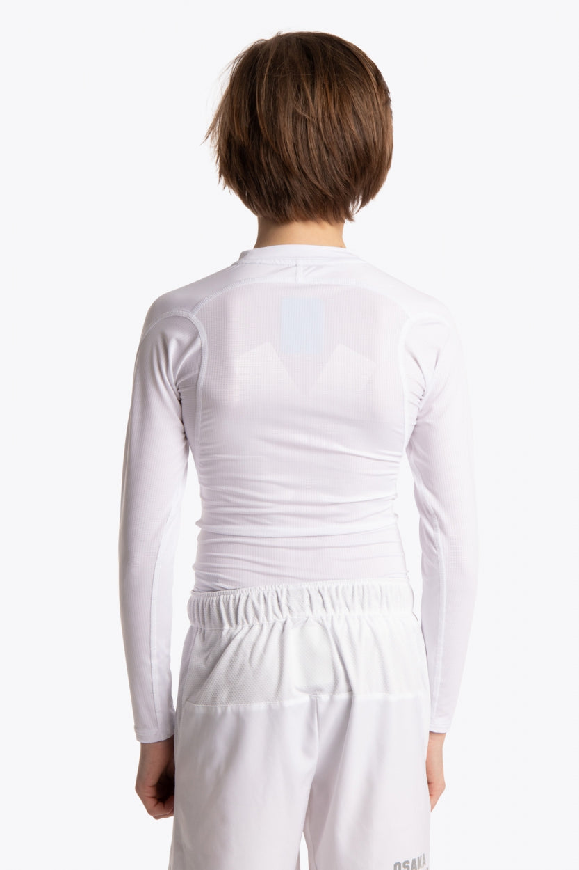 Boy wearing the Osaka Kids Baselayer Top in white. Back view