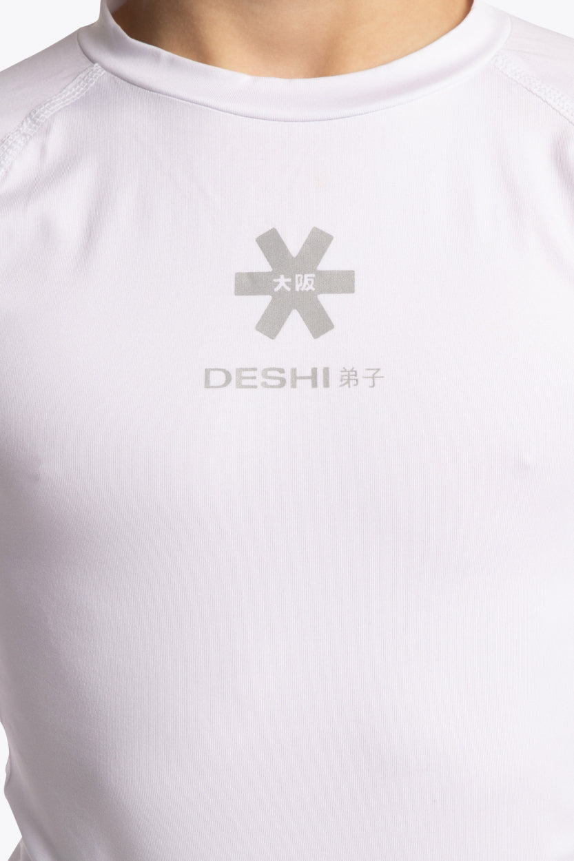 Model wearing the Osaka Kids Baselayer Top in white. Front detail logo view