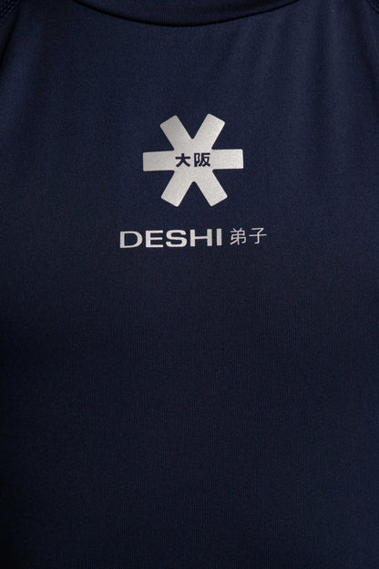 Model wearing the Osaka Kids Baselayer Top in Navy. Front detail logo view