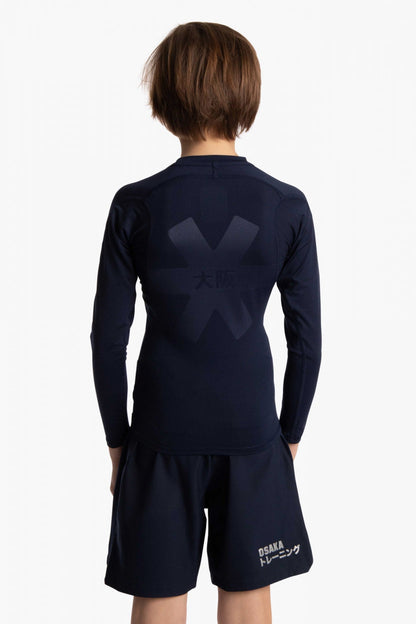 Boy wearing the Osaka Kids Baselayer Top in Navy. Back view