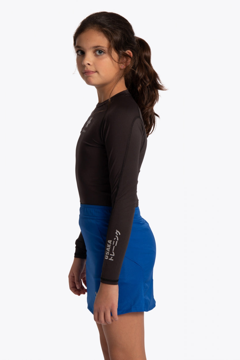 Kid wearing the Osaka Kids Baselayer Top in Black. Side view