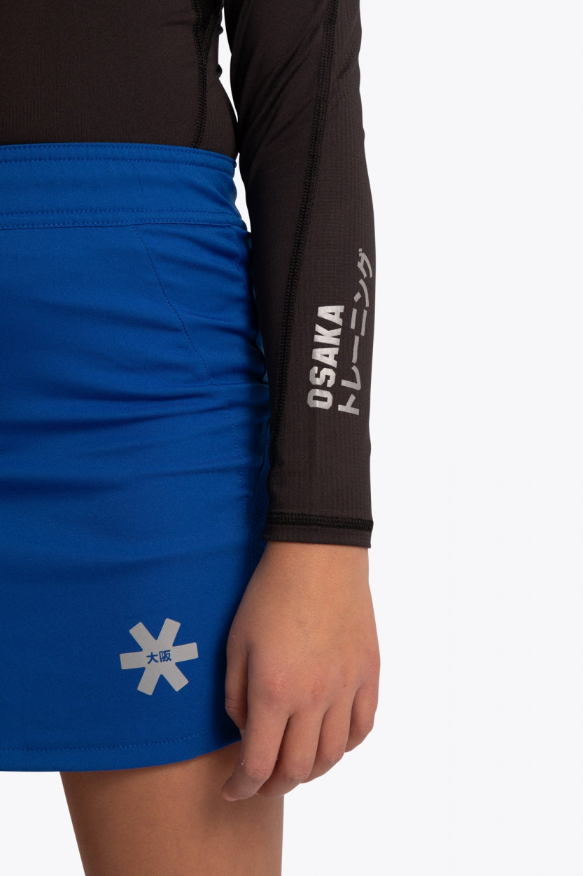 Kid wearing the Osaka Kids Baselayer Top in Black. Front detail logo sleeveview