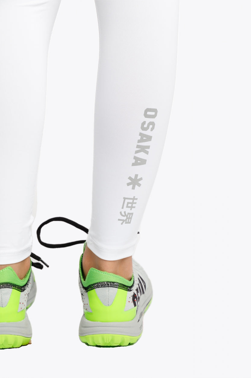 Model wearing the Osaka Kids Baselayer Tights in White. Detail back logo view