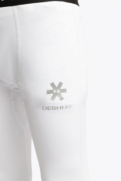 Model wearing the Osaka Kids Baselayer Tights in White. Detail front logo view