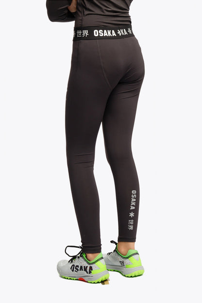 Model wearing the Osaka Kids Baselayer Tights in Black. Back view